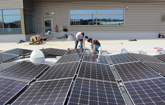 Two students work on constructing a solar panel array.