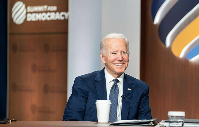President Joe Biden smiling as he hosts the virtual Summit for Democracy.