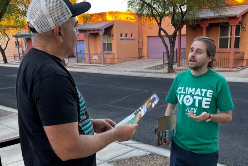 A Climate Vote canvasser speaks to a member of the public on their front porch.