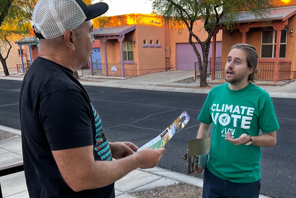 A Climate Vote canvasser speaks to a member of the public on their front porch.