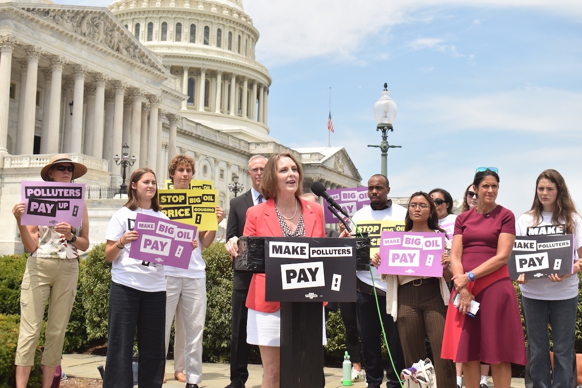 Rep. Kathy Castor speaks at a Polluters Pay press conference in front of the capitol with many people holding signs around her.